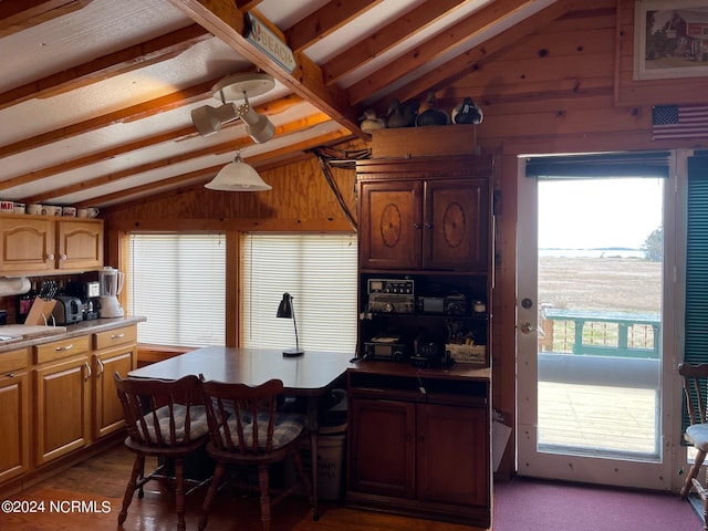 kitchen with lofted ceiling with beams, wood walls, and light countertops