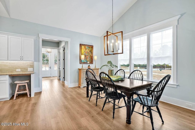 dining area with high vaulted ceiling, a chandelier, and light hardwood / wood-style floors