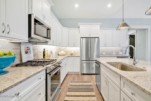 kitchen featuring white cabinetry, premium appliances, decorative light fixtures, and light stone countertops