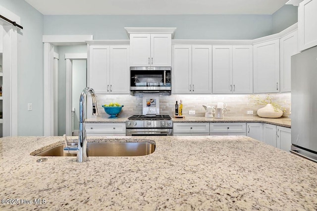 kitchen featuring white cabinetry, sink, light stone counters, and appliances with stainless steel finishes