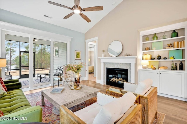 living room with built in shelves, ceiling fan, high vaulted ceiling, and light hardwood / wood-style floors