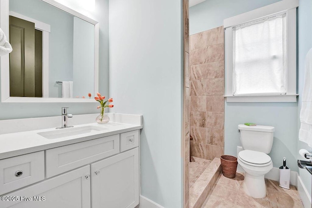 bathroom featuring vanity, a tile shower, and toilet