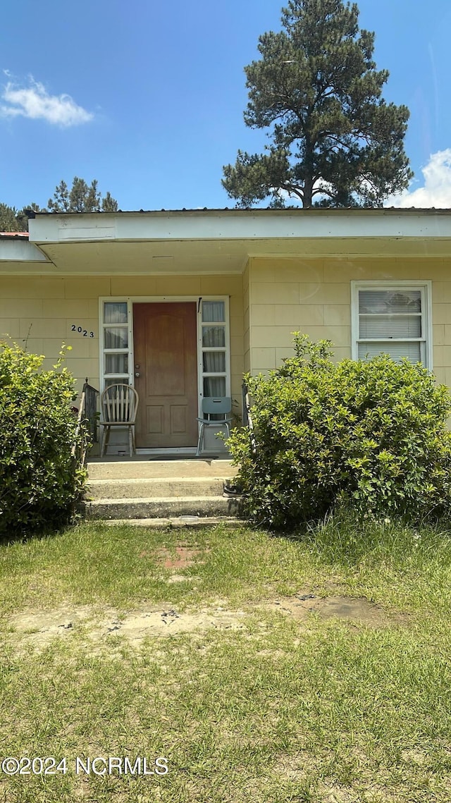 view of exterior entry with a lawn