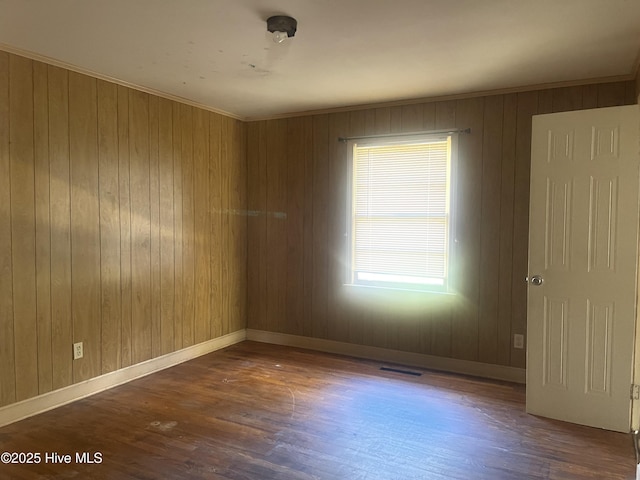 spare room with crown molding, dark hardwood / wood-style flooring, and wood walls