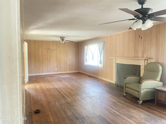 unfurnished room featuring ceiling fan, dark wood-type flooring, a textured ceiling, and wood walls