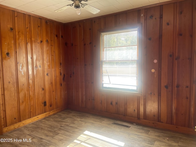 spare room with wooden walls, light hardwood / wood-style floors, and ceiling fan