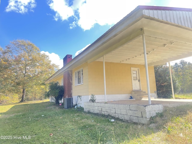 view of home's exterior featuring central AC unit, a yard, and a carport