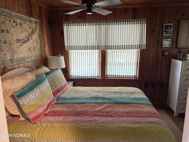 bedroom featuring multiple windows, wood walls, and ceiling fan