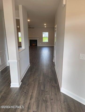 corridor featuring baseboards and dark wood-style flooring