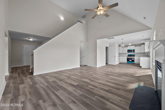 200 Slater Way, Jacksonville, NC 28540 - unfurnished living room with high vaulted ceiling, ceiling fan, wood finished floors, baseboards, and a sink