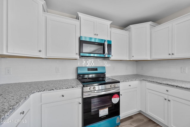 kitchen with white cabinets, appliances with stainless steel finishes, and light wood-type flooring