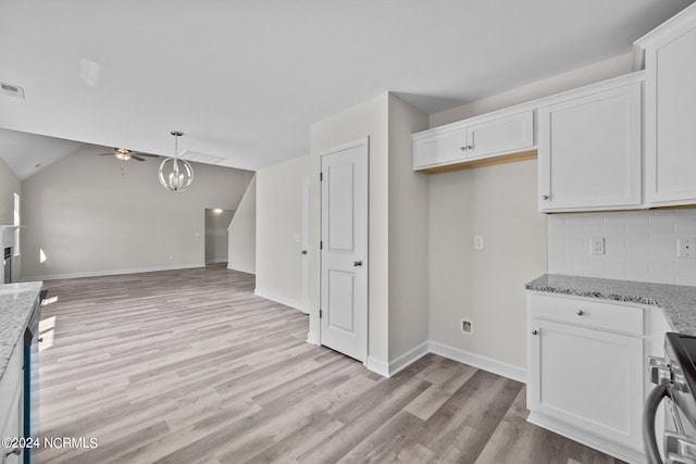 kitchen featuring white cabinetry, backsplash, light stone countertops, light wood-type flooring, and stainless steel range oven