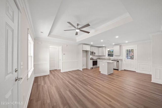 unfurnished living room with ornamental molding, sink, ceiling fan, a raised ceiling, and light hardwood / wood-style floors