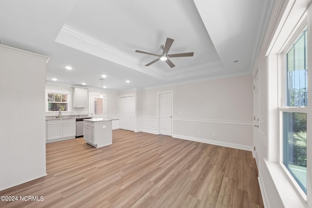 unfurnished living room with a tray ceiling, plenty of natural light, and ceiling fan