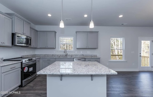 kitchen with gray cabinets, a breakfast bar, pendant lighting, sink, and stainless steel appliances