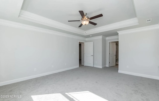 unfurnished bedroom with ceiling fan, light colored carpet, ornamental molding, and a tray ceiling