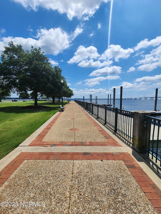 surrounding community featuring a water view and a lawn