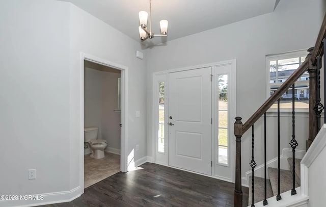 foyer entrance with dark wood-type flooring and an inviting chandelier