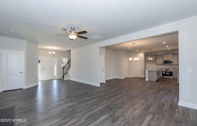 unfurnished living room featuring ceiling fan with notable chandelier and dark hardwood / wood-style flooring