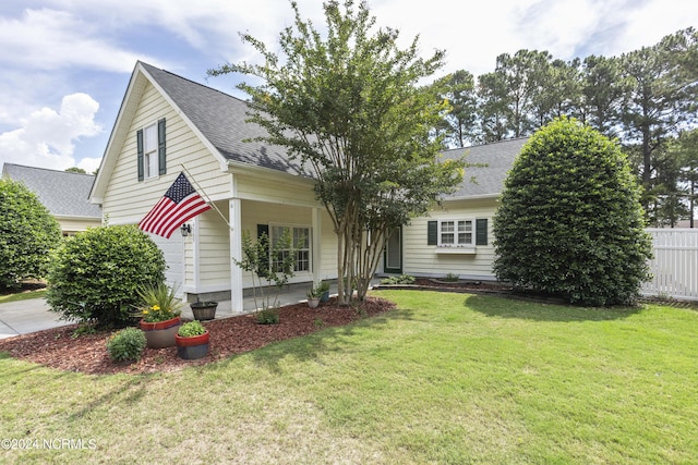 view of front of house with roof with shingles, fence, and a front lawn