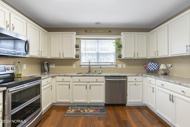 kitchen featuring appliances with stainless steel finishes, white cabinetry, a sink, and dark wood-type flooring