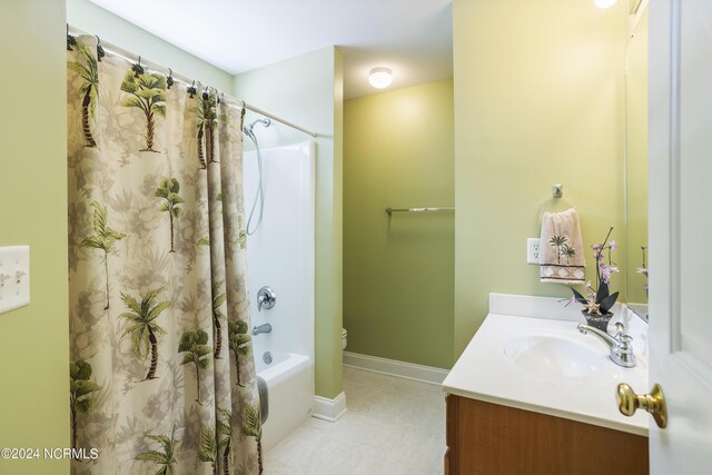 bathroom with toilet, vanity, baseboards, tile patterned floors, and shower / bath combo