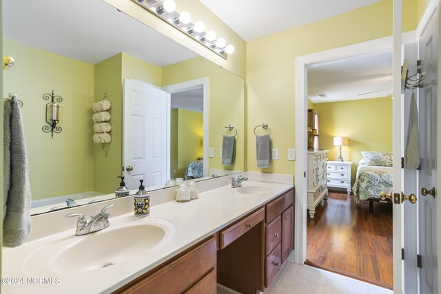 ensuite bathroom with double vanity, ensuite bath, and a sink