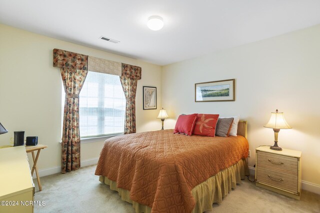 bedroom with light carpet, visible vents, and baseboards