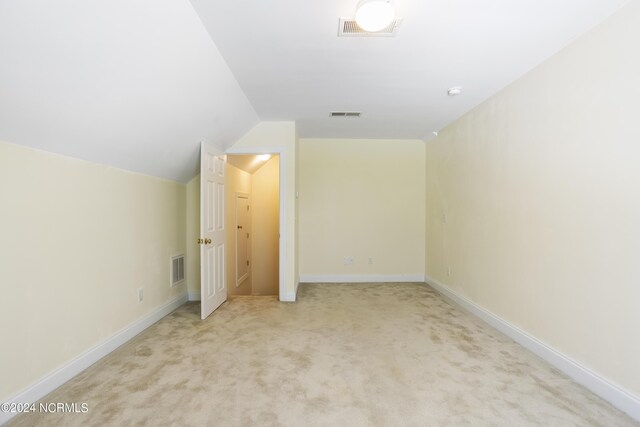 unfurnished bedroom with light colored carpet, lofted ceiling, and visible vents