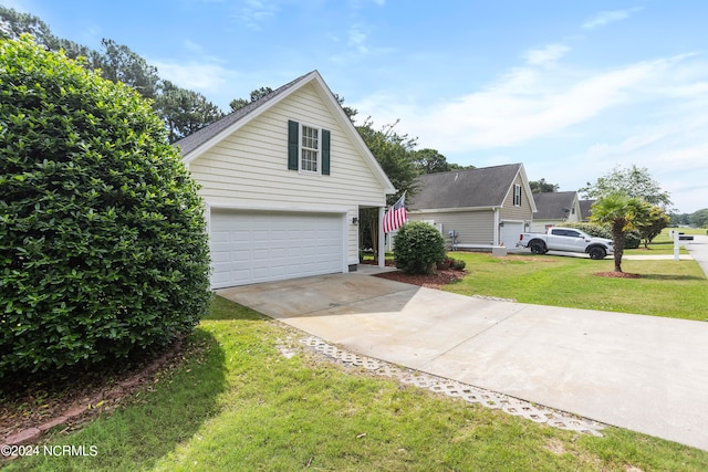 view of side of home featuring concrete driveway and a yard