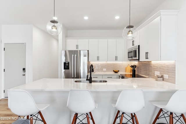 kitchen featuring sink, hanging light fixtures, appliances with stainless steel finishes, and a breakfast bar area