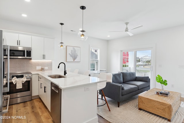 kitchen with white cabinetry, sink, tasteful backsplash, kitchen peninsula, and appliances with stainless steel finishes