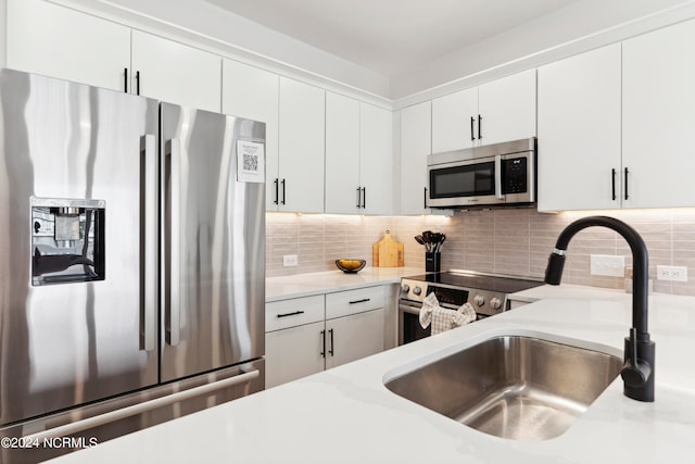 kitchen with decorative backsplash, sink, white cabinets, and stainless steel appliances