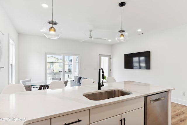 kitchen with dishwasher, sink, light stone counters, light hardwood / wood-style floors, and pendant lighting