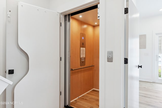 corridor featuring light wood-type flooring and elevator