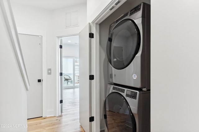 laundry area featuring stacked washer and dryer and light hardwood / wood-style flooring