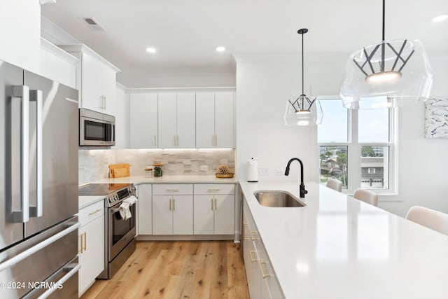 kitchen featuring tasteful backsplash, stainless steel appliances, sink, white cabinets, and hanging light fixtures