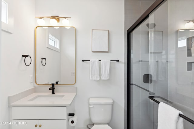 bathroom with vanity, toilet, and a shower with shower door