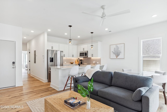 living room with light hardwood / wood-style flooring and ceiling fan