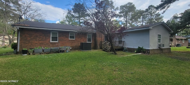 back of property featuring a wooden deck, central AC unit, and a lawn