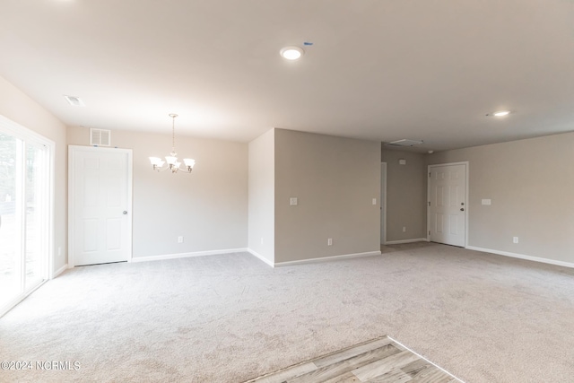 unfurnished room featuring carpet floors and an inviting chandelier