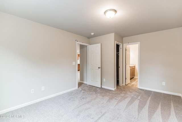 unfurnished bedroom with carpet, a closet, and ensuite bathroom