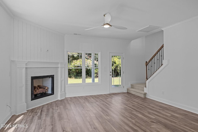 unfurnished living room with crown molding, wood-type flooring, a brick fireplace, and ceiling fan