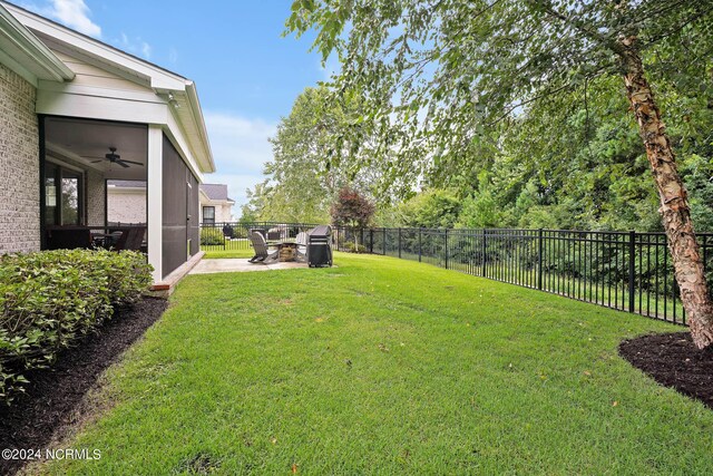 back of house featuring ceiling fan, a lawn, an outdoor fire pit, and a sunroom