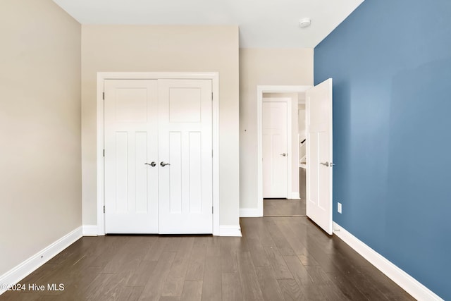 unfurnished bedroom featuring dark hardwood / wood-style floors and a closet