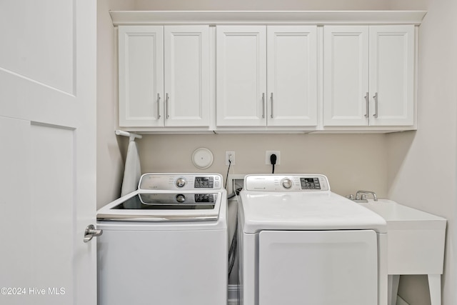 clothes washing area with cabinets, sink, and washing machine and clothes dryer