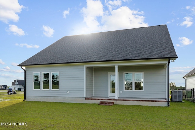 rear view of property featuring cooling unit and a lawn