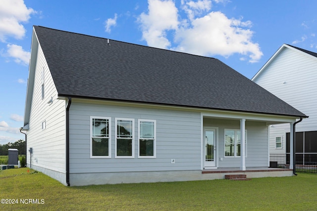 back of property with covered porch and a yard