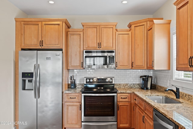 kitchen with sink, stainless steel appliances, tasteful backsplash, and light stone counters