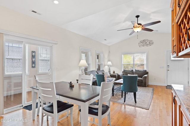 dining space with ceiling fan, light hardwood / wood-style flooring, and vaulted ceiling